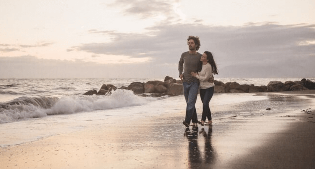 Two adults walking beside the ocean